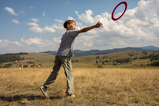 Boy Throwing Frisbee in a Sunny Field During Afternoon Play