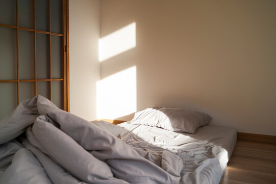 Minimal Japanese style bedroom with morning light on futon