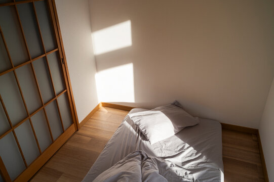 Minimal Japanese style bedroom with morning light on futon