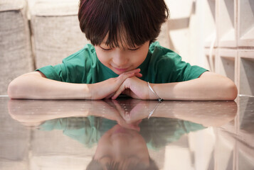 Chinese boy lies on the reflective coffee table at home