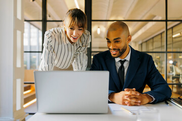 Formal business people collaborating on laptop, working in office