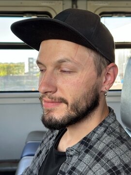 A funny, sleepy young man on a train with a sleep mark on his face
