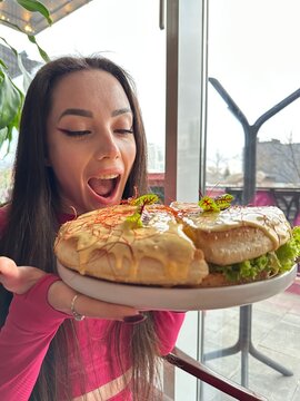 A young woman bites into a large cheese burger cake