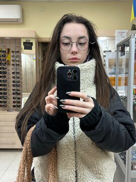 A woman tries on glasses at an optical store to choose the best ones.