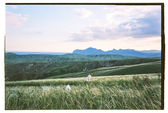Film photo of a little girl running across the field with her dog