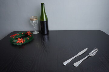 Christmas festive holiday decoration and some traditional food such as roasted chicken turkey, wine bottle and glass on black wooden table. Blank background mockup with copy space for adding text