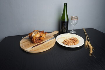 Christmas festive holiday decoration and some traditional food such as roasted chicken turkey, wine bottle and glass on black wooden table. Blank background mockup with copy space for adding text