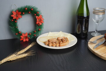 Christmas festive holiday decoration and some traditional food such as roasted chicken turkey, wine bottle and glass on black wooden table. Blank background mockup with copy space for adding text