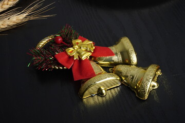 Christmas gift boxes with red and green ribbon, wreath garland, candy cane, santa sock, bauble and golden bells on black wooden table. Blank background mockup with copy space for adding text
