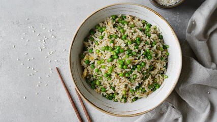 Healthy vegetable fried rice with green peas in a rustic ceramic bowl with chopsticks. Cinematic 360 orbit rotation for organic food and vegetarian lifestyle ads.