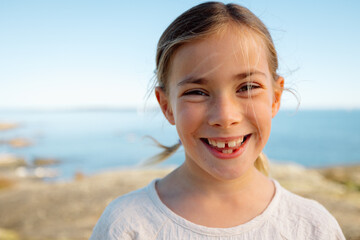 Candid smile of a young girl by the sea, bright moment