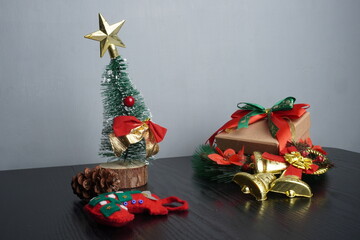 Christmas gift boxes with red and green ribbon, wreath garland, candy cane, santa sock, bauble on black wooden table with festive holiday decoration and some traditional food. Blank background mockup 