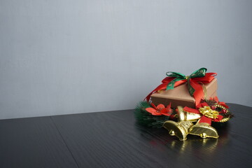 Christmas gift boxes with red and green ribbon, wreath garland, candy cane, santa sock, bauble and golden bells on black wooden table. Blank background mockup with copy space for adding text