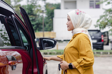 A young Indonesian Muslim woman opening her car door