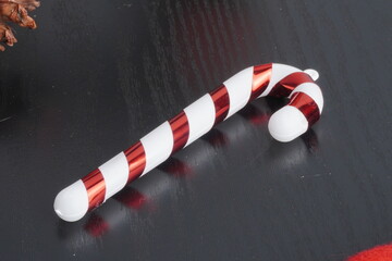 Christmas gift boxes with red and green ribbon, wreath garland, candy cane, santa sock, bauble and golden bells on black wooden table. Blank background mockup with copy space for adding text