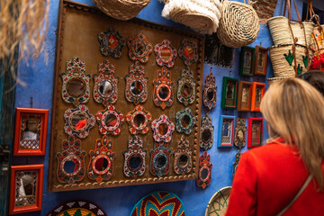 Anonymous woman browsing items outside a shop in Chefchaouen