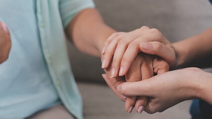 Doctor, patient and holding hands on desk in consultation room with support, empathy and announcement. Medic, person and care with comfort, diagnosis and helping with healthcare service at hospital