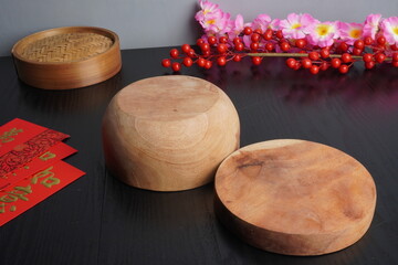 Empty background of a dark wooden tabletop with cherry blossom decorations, a bamboo dimsum steamer, and an empty plate for Chinese Lunar New Year celebration.