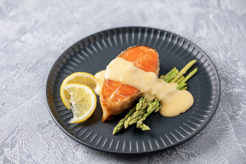Steak salmon grill with asparagus sprouts, with hollandaise sauce in a plate on the table