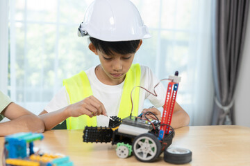 Boy wearing hard hat with safety vest assembling a robotic car, representing STEM education, engineering skills, early learning in robotics and innovation for kids.
