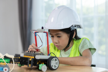Focused young girl wearing hard hat and safety vest building a robotic vehicle, symbolizing STEM education, innovation and hands on learning in engineering and technology for kids.