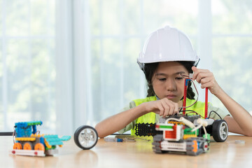 Focused young girl wearing hard hat and safety vest building a robotic vehicle, symbolizing STEM education, innovation and hands on learning in engineering and technology for kids.