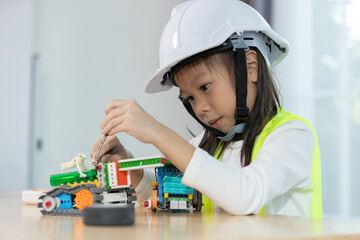 Focused young girl wearing hard hat and safety vest building a robotic vehicle, symbolizing STEM education, innovation and hands on learning in engineering and technology for kids.