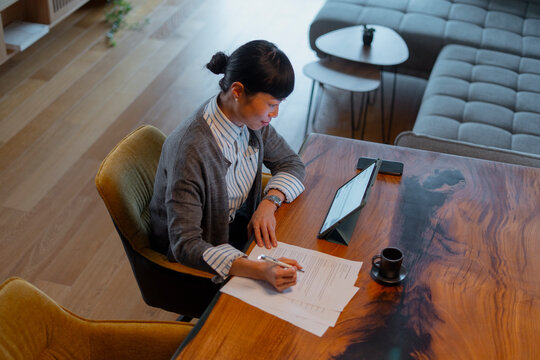 Woman working remotely signing contract documents at home
