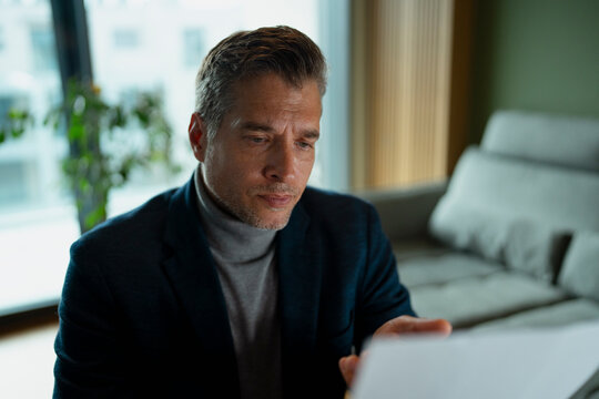 Mature businessman reading focusing analyzing business document
