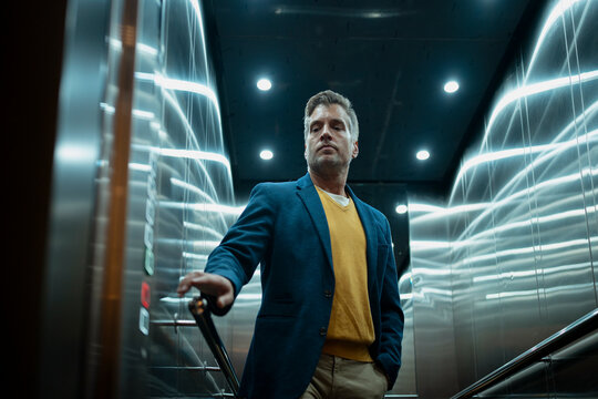 Pensive businessman standing in an elevator looking thoughtful
