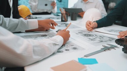 A diverse team of engineers engaged in a collaborative discussion, reviewing blueprints and project plans in a modern office environment, showcasing teamwork. SACTR
