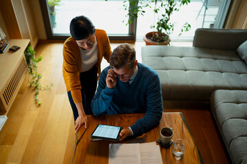 Mature couple calculating household budget with digital tablet at home
