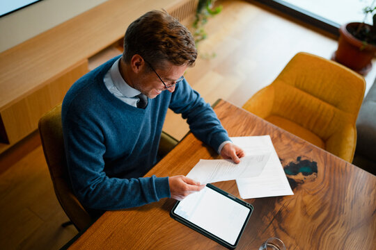 Businessman reading document, checking details on digital tablet
