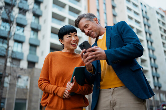 Diverse business partners sharing screen on smartphone
