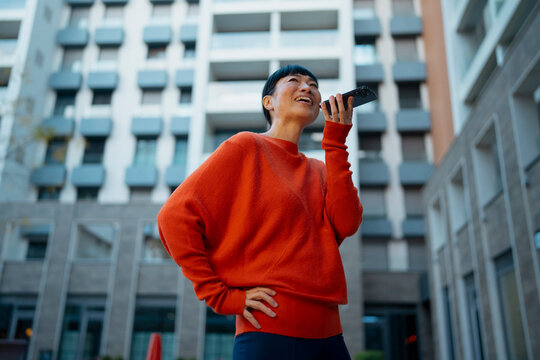 Woman sending voice message on smartphone in city
