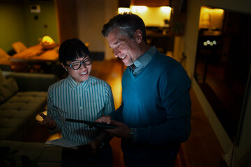 Diverse coworkers collaborating on tablet working late in office
