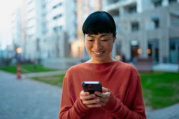 Smiling woman using smartphone in urban street