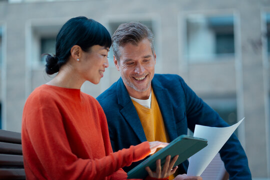 Diverse colleagues discussing business documents outdoors
