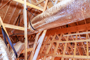 Workers install metal ductwork in ceiling of building that is being constructed