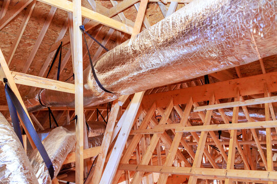 Workers install metal ductwork in ceiling of building that is being constructed