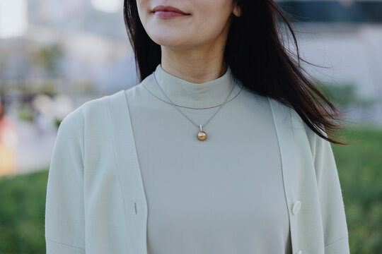 Woman wearing golden pearl necklace outdoors