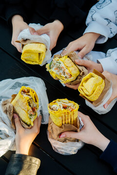 A group of friends enjoys shawarma at an outdoor table