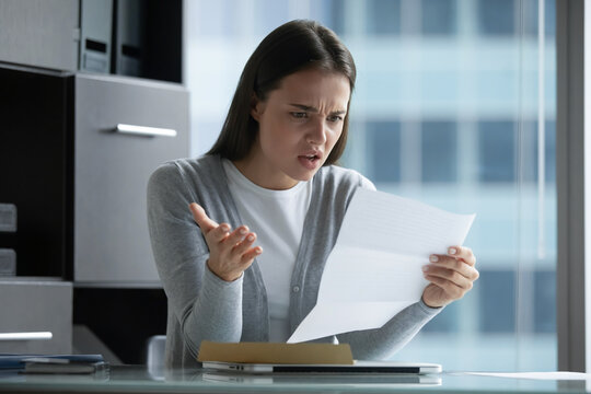 Bad news received. Mad angry millennial woman business professional corporate manager student hold paper letter bank notice feel outraged by rejected business proposal declined loan failed exam result