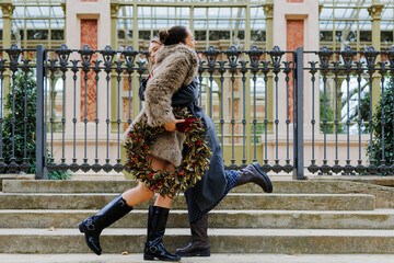 Women hugging carrying christmas wreath on the city street