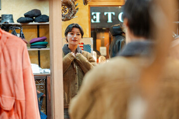 Young woman trying on vintage jacket in Japanese clothing store
