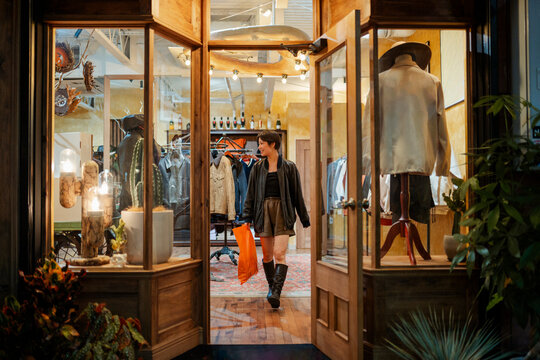 Woman leaving vintage clothing store with shopping bag