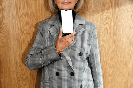 Person holding smartphone with blank screen in front of chest