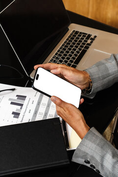 Businessperson holding smartphone with blank screen at desk