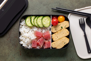 Asian bento box with rice, tuna, omelette tamagoyaki and vegetables. Healthy snack in the office or school. Top view