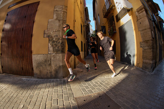 Runners enjoying a sunny morning in a narrow street